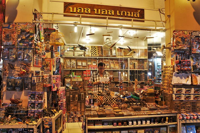 Toy Shop Scene at Chiang Mai Street Food Night Markets Shopkeeper browsing toys and stationery in a busy toy shop display at Chiang Mai Street Food Night Markets.