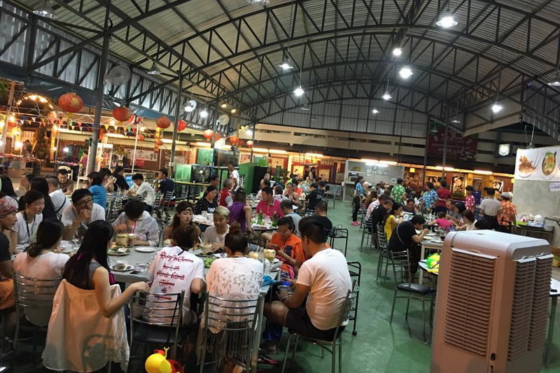 Indoor Market Dining Scene at Chiang Mai Street Food Night Markets Indoor market dining area with many people eating and food stalls in the background at Chiang Mai Street Food Night Markets.