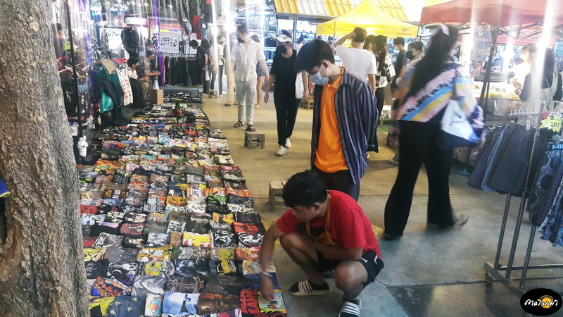 Market Stall with Fabric Items at Best Night Markets In Chiang Mai Person browsing fabric items at an outdoor market with shoppers and stalls around at Best Night Markets In Chiang Mai.