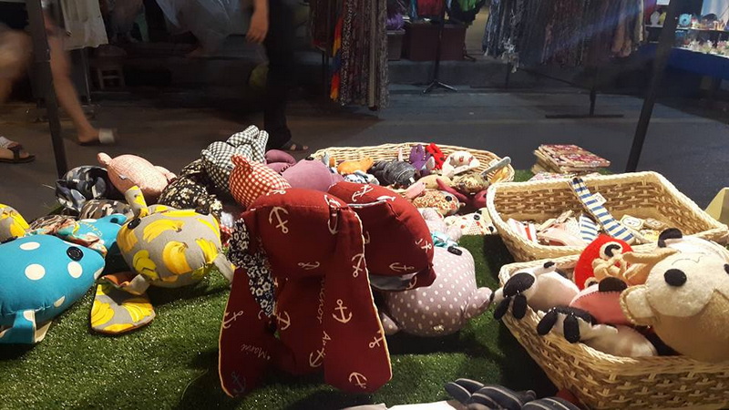 Market stall with colorful fabric pouches and stuffed toys on display at Saturday Walking Street Chiang Mai.