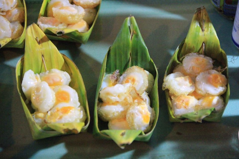 Three banana leaf packages filled with small fried eggs on a surface at Wua Lai Walking Street Chiang Mai.