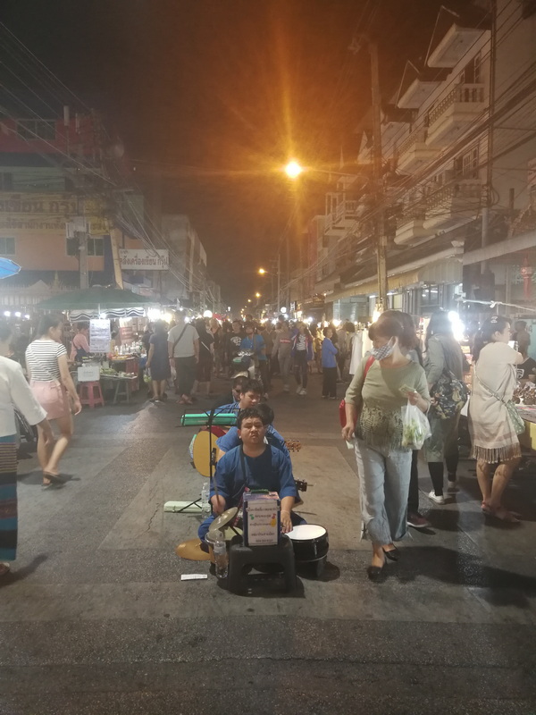People walking and shopping at night market under streetlights at Saturday Walking Street Chiang Mai.