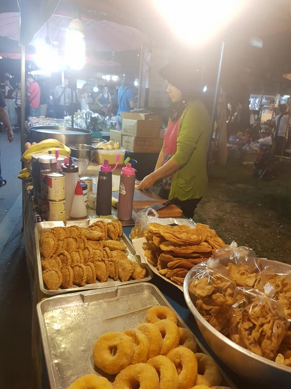 Night Market Food Stall Scene at Saturday Night Market Chiang Mai A woman preparing fried snacks at a bustling night market stall with crowd in background at Saturday Night Market Chiang Mai.