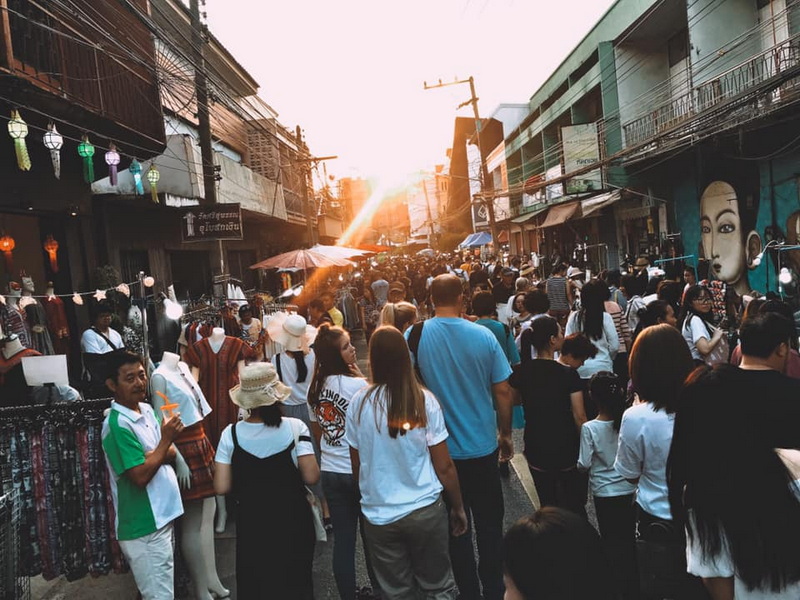 Busy street market with lanterns and shoppers during sunset at Saturday Night Market Chiang Mai.