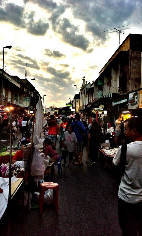 Bustling Chiang Mai Night Market at Sun Day Walking Street Chiang Mai Street market scene with vendors, shoppers, and shops under cloudy sky in Chiang Mai at Sun Day Walking Street Chiang Mai.