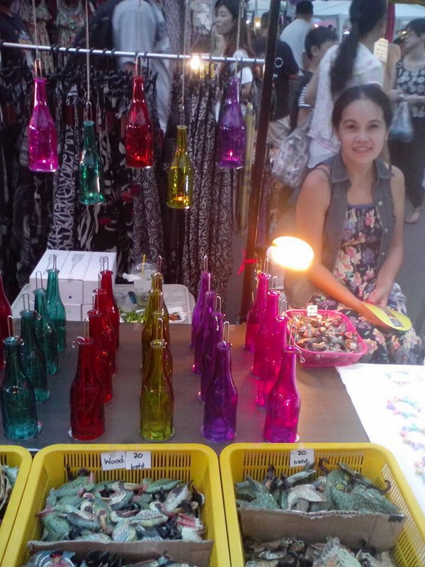 Street Market Scene with Bottles and Seafood at Chiang Mai Night Markets Woman sitting at a street market stall with colorful bottles and seafood displays at Chiang Mai Night Markets.