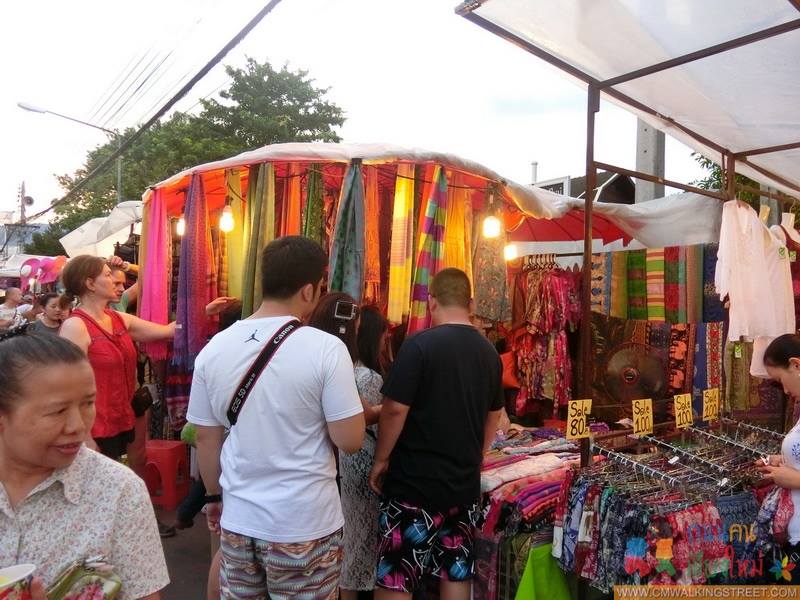Outdoor Fabric Market Scene at Sunday Night Market Chiang Mai People shopping at a vibrant outdoor fabric and clothing market stall at Sunday Night Market Chiang Mai.