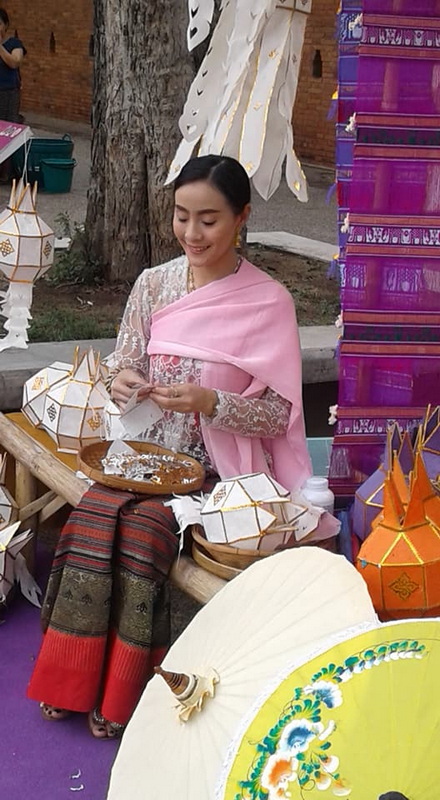 Traditional Thai Market Scene at Sunday Market Chiang Mai Woman in traditional Thai clothing selling paper lanterns at an outdoor market at Sunday Market Chiang Mai.