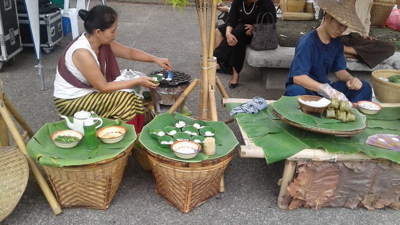 Street Food Vendors at Sunday Market Chiang Mai Street food vendors preparing dishes with banana leaves and baskets on a city street at Sunday Market Chiang Mai.