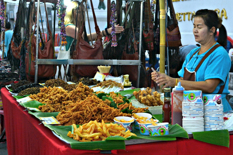 Outdoor Market Food Stall at Sun Day Walking Street Chiang Mai Woman selling fried snacks at an outdoor market stall with bags hanging above at Sun Day Walking Street Chiang Mai.