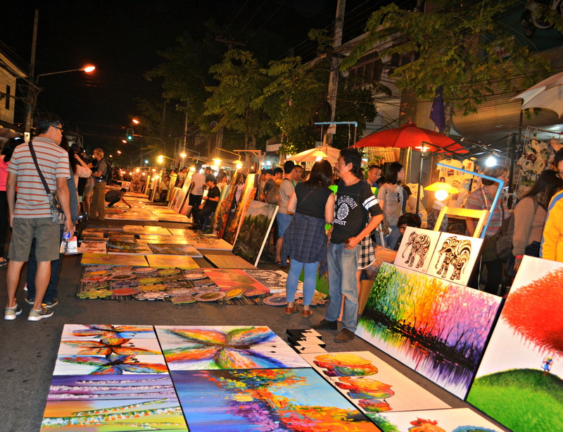 Street market with colorful paintings displayed on stalls at night in Chiang Mai at Sunday Market Chiang Mai.