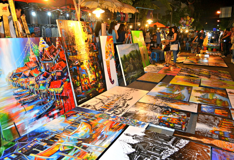 Night Market Art Display at Sunday Market Chiang Mai Colorful paintings displayed at a lively outdoor night market scene at Sunday Market Chiang Mai.