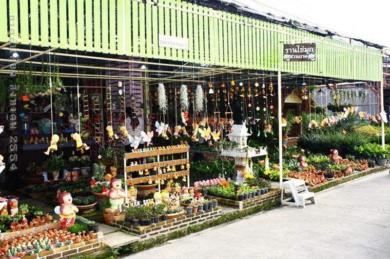 Decorative Figurine Shop Scene at Shopping In Chiang Mai Storefront with colorful figurines and hanging decorations under a green roof at Shopping In Chiang Mai.
