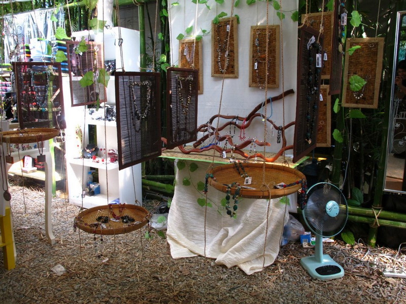 Jewelry displayed on hanging frames and bamboo trays with green foliage in background at Nimmanhaemin road.
