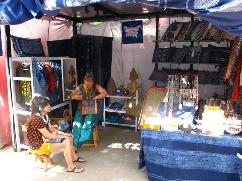 Woman and girl seated in market stall with fabric and accessories on display at Nimmanhaemin road.
