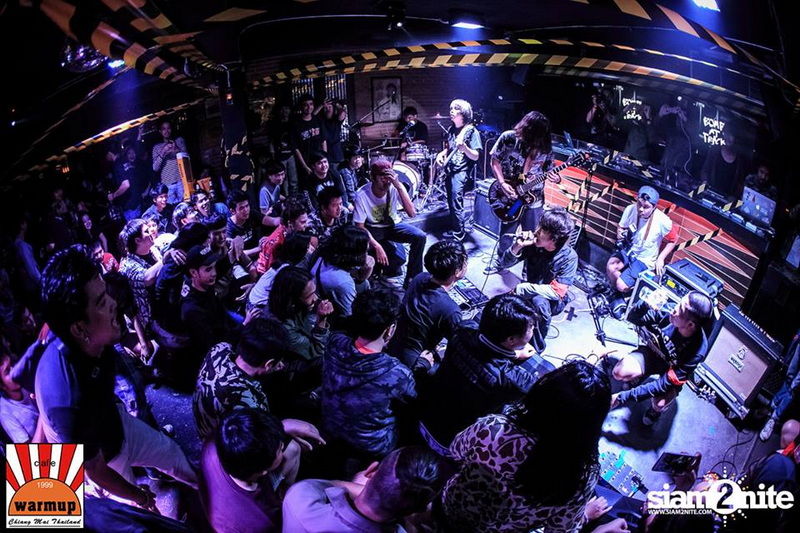Live band performing on stage with an audience watching in a dark venue at Nimmanhaemin road.