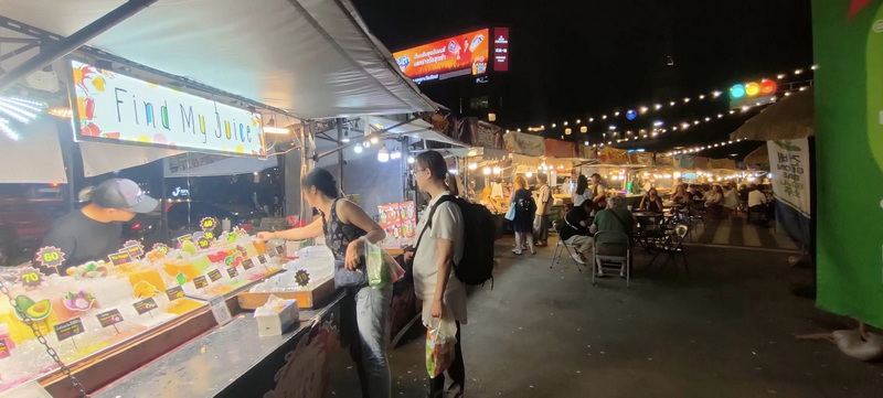 Night market with food stalls and people shopping under string lights at Nimmanhaemin road.