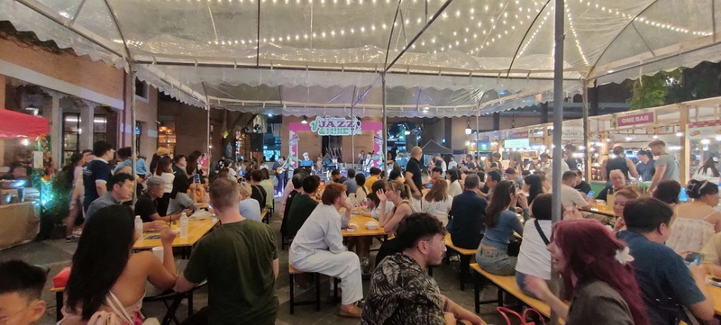 Live Music Event Scene at Nimmanhaemin road Indoor event with people enjoying music and food under string lights at Nimmanhaemin road.