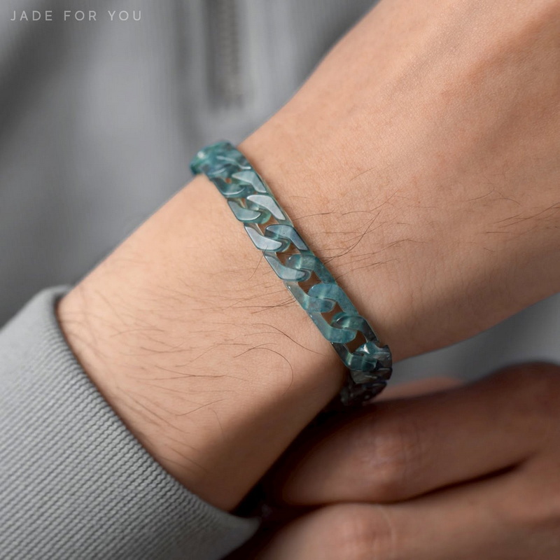 Close-up of a wrist wearing a blue-gray chain bracelet against a blurred gray background at Orchid Jade Factory.
