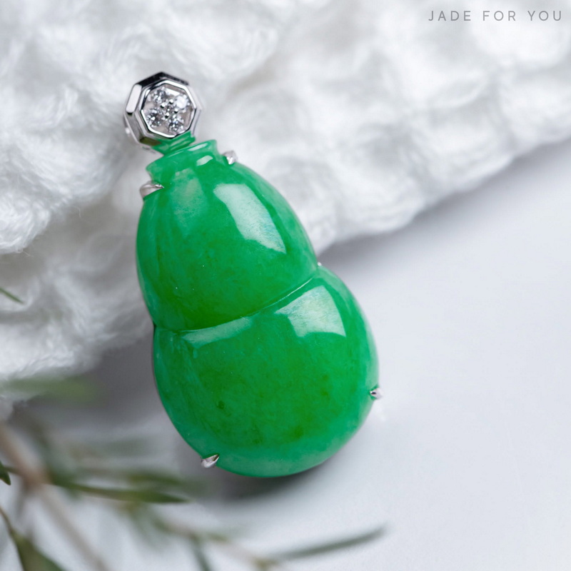 Close-up of a green jade beetle-shaped pendant with silver details on a white background at Orchid Jade Factory.