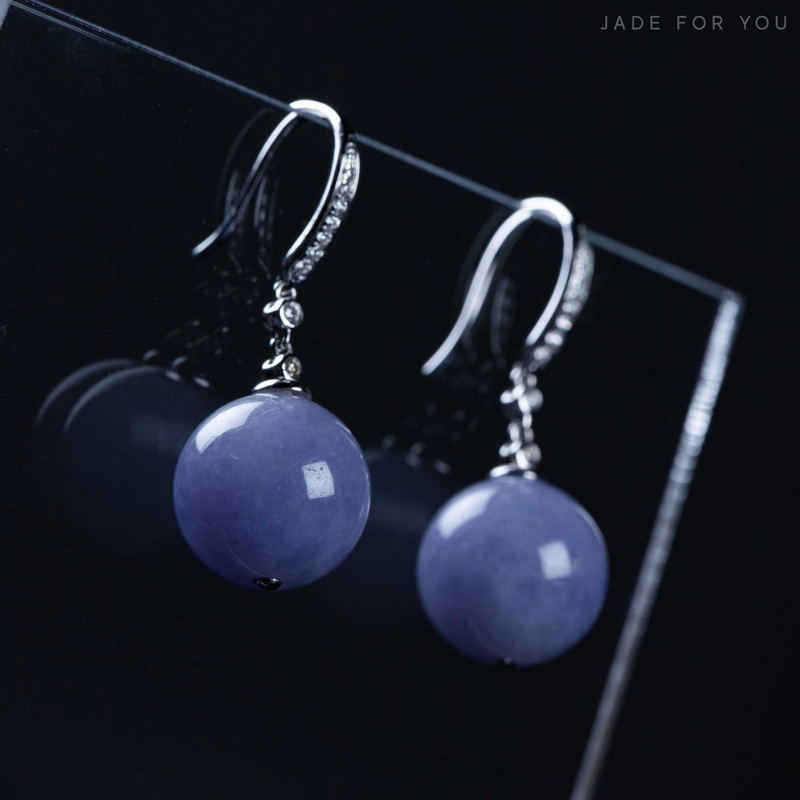 Silver earrings with purple spherical stones hanging from hooks against a dark background at Chiang Mai Jade Factory.
