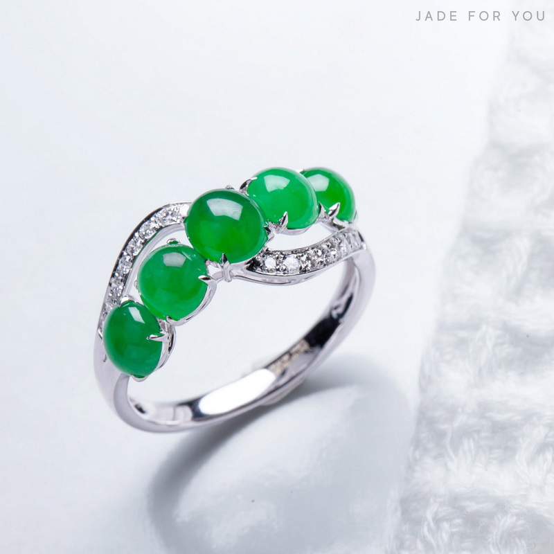 Silver ring featuring six green jade stones and embedded diamonds in a close-up shot at Orchid Jade Factory.
