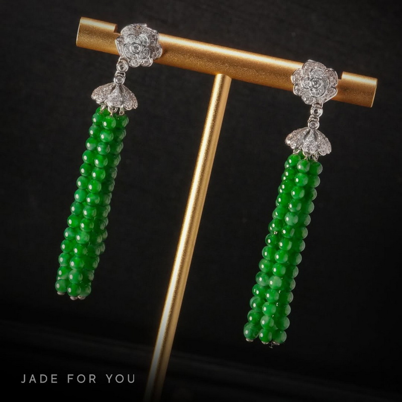 Pair of green beaded earrings with floral gemstone tops on a gold stand at Chiang Mai Jade Factory.