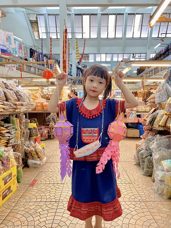 Girl with Lanterns in Market at Souvenir Shopping Chiang Mai Young girl wearing traditional dress holding lanterns inside a vibrant market stall at Souvenir Shopping Chiang Mai.