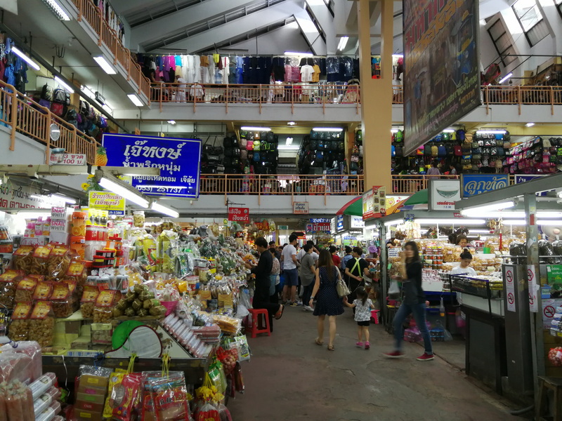 Inside a crowded market with stalls selling goods and shoppers browsing at Warorot Market.