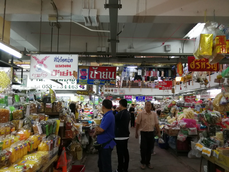 Busy Indoor Market Scene at Best Street Food Markets In Chiang Mai Indoor market with stalls selling snacks and people shopping at Best Street Food Markets In Chiang Mai.