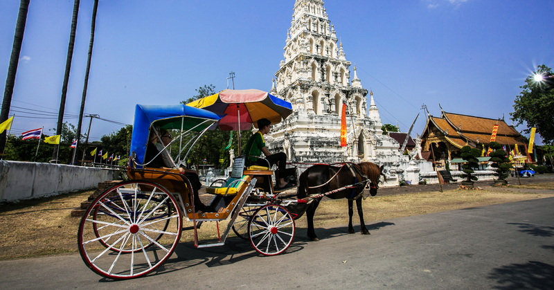 Chiang Mai Temple Scene at Chiang Mai Cruise To Wiang Kum Kam Horse-drawn carriage passing a white temple tower in Chiang Mai during daytime at Chiang Mai Cruise To Wiang Kum Kam.
