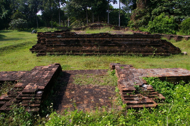 Ancient brick ruins with grassyground and trees around in an open area at Chiang Mai Cruise To Wiang Kum Kam.