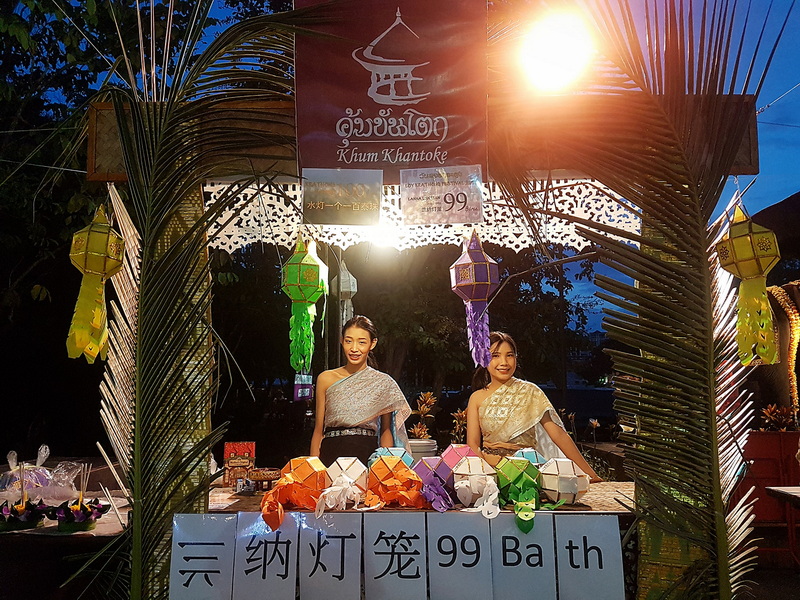 Lantern Display Event at Khum Khantoke Two women in traditional dresses at a lantern display booth during dusk at Khum Khantoke.