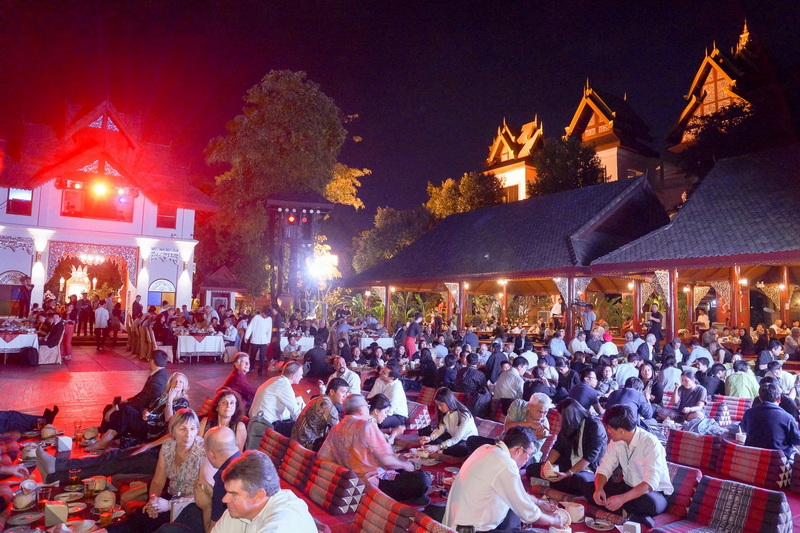 Night Dining Scene at Khantoke People dining on cushions under traditional Thai-style structures at night at Khantoke.