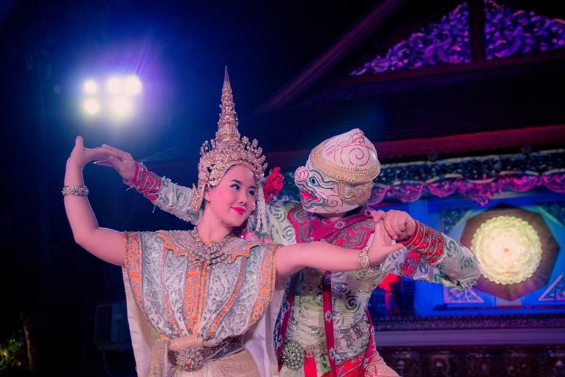 Performers in traditional costumes dancing on a decorated stage with colorful lighting at Khantoke.