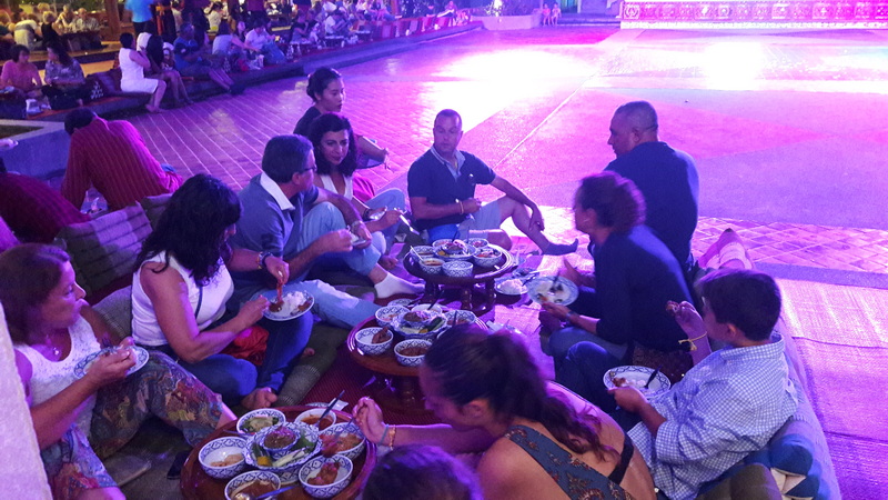 Group Dining Experience at Khantoke Group of people enjoying a meal with food on low tables in a spacious, lit area at Khantoke.