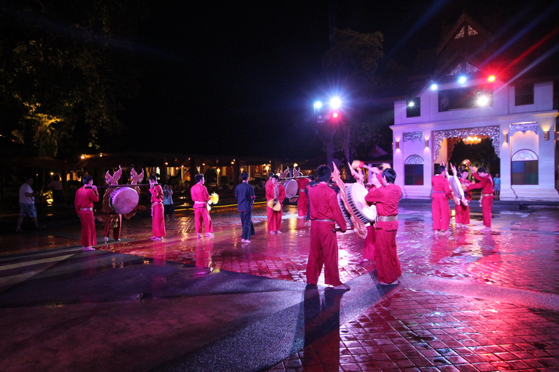 Performers in pink costumes playing drums and traditional instruments at night at Khantoke Dinner.