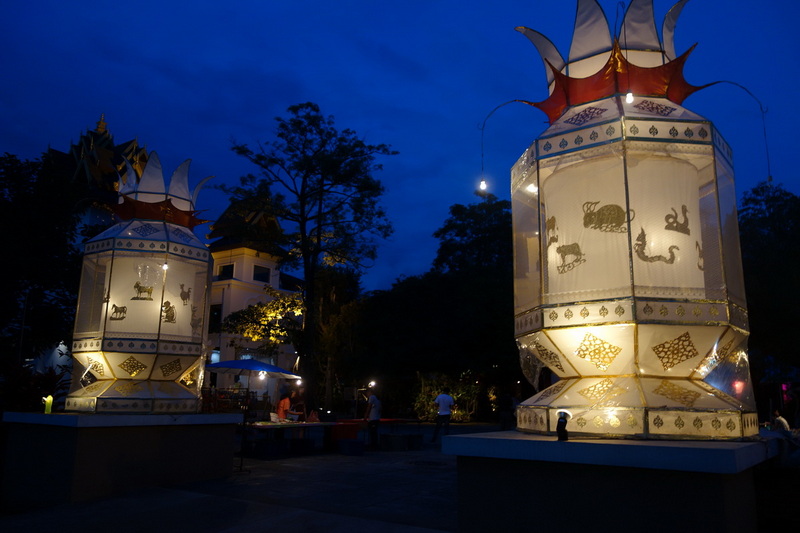 Two decorated lanterns illuminated at night with animal patterns in a natural outdoor setting at Khum Khantoke.