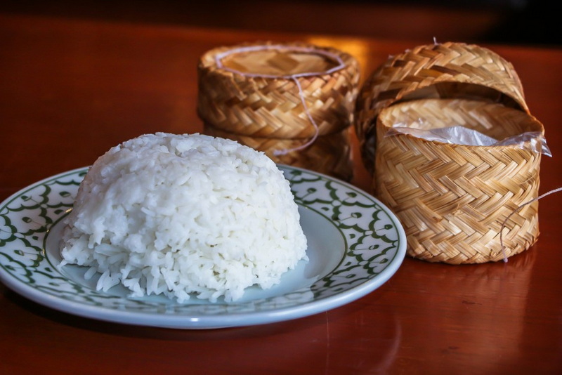 Sticky Rice with Bamboo Containers at Khum Khantoke Plate of white sticky rice with small bamboo containers on a wooden table at Khum Khantoke.