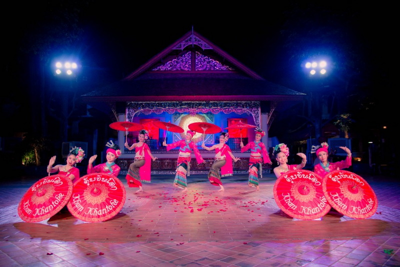 Traditional Dance Performance at Khum Khantoke Six women dancing with umbrellas on stage at night during a traditional performance at Khum Khantoke.