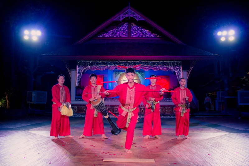 Performers in red traditional costumes dance on stage with colorful lighting at Khum Khantoke.