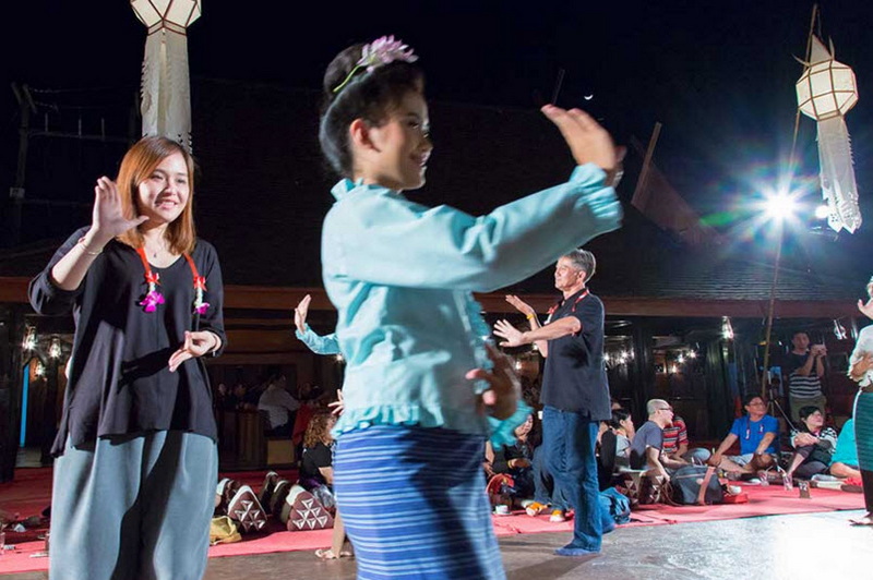 Traditional Dance Performance at Old Chiangmai Cultural Center Group of people dancing in traditional attire with lanterns overhead at night at Old Chiangmai Cultural Center.
