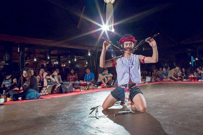 Traditional Cultural Performance Scene at Old Chiangmai Cultural Center Performer dressed in traditional costume with staff kneeling on stage in front of seated audience at Old Chiangmai Cultural Center.
