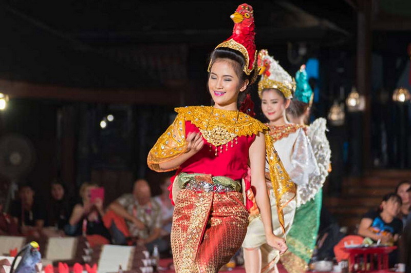 Traditional Thai Cultural Performance at Old Chiangmai Cultural Center Khantoke Woman in traditional Thai dress smiling during stage performance with audience in background at Old Chiangmai Cultural Center Khantoke.