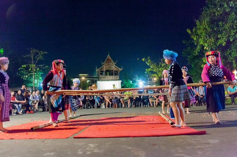 Cultural Bamboo Stick Dance Night Show at Old Chiangmai Cultural Center Women in traditional clothing performing bamboo stick dance at night with audience watching at Old Chiangmai Cultural Center.