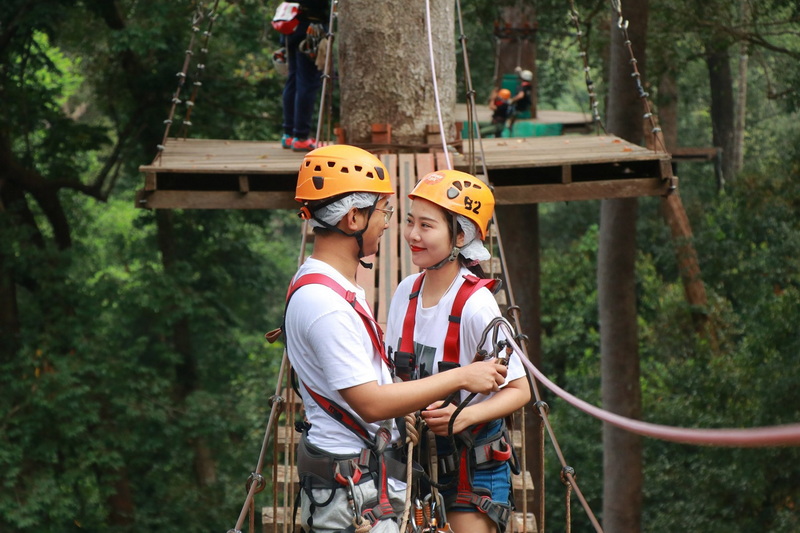 Forest Adventure in Chiang Mai at Jungle Flight Zipline Chiang Mai Two women with helmets and harnesses chatting on a platform in the forest at Jungle Flight Zipline Chiang Mai.