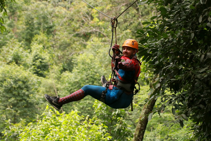 Person ziplining through lush green forest with safety gear on at Jungle Flight Zipline Chiang Mai.
