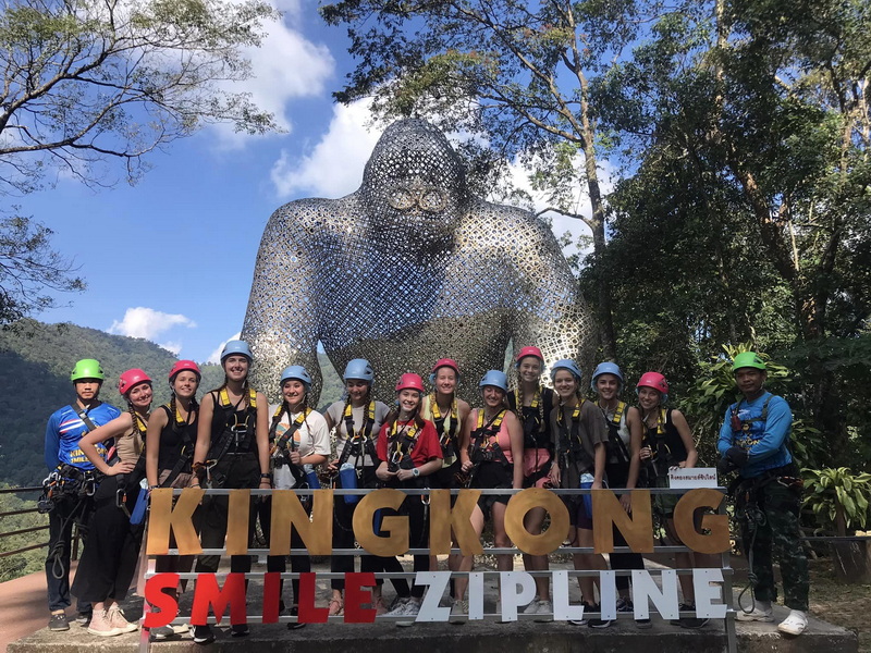 Group at Gorilla Sculpture at Kingkong Smile Zipline Group of people standing in front of a large metal gorilla sculpture outdoors at Kingkong Smile Zipline.