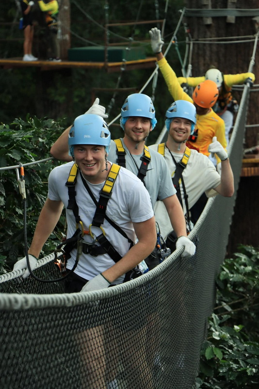 Group on Zipline Platform at Kingkong Smile Zipline Group of four people on a zipline platform wearing helmets and harnesses, smiling at the camera at Kingkong Smile Zipline.