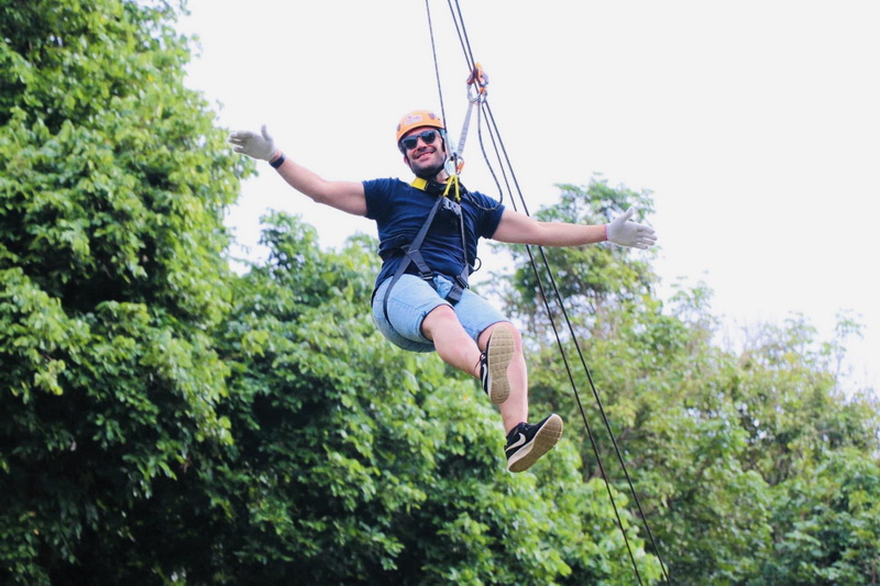 Zip Line Adventure at Phoenix Zipline Chiang Mai Person with helmet and harness swinging on a zip line over trees at Phoenix Zipline Chiang Mai.